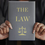 Hands, woman or judge with book called "The Law"
