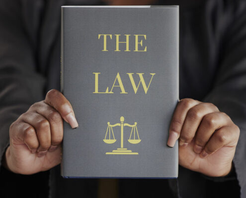 Hands, woman or judge with book called "The Law"